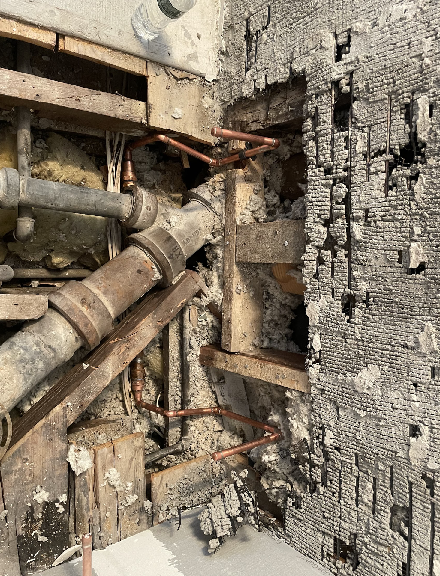 New black ABS drain piping with branch connections mounted on exposed original brick wall in a Bedford-Stuyvesant pre-war commercial building