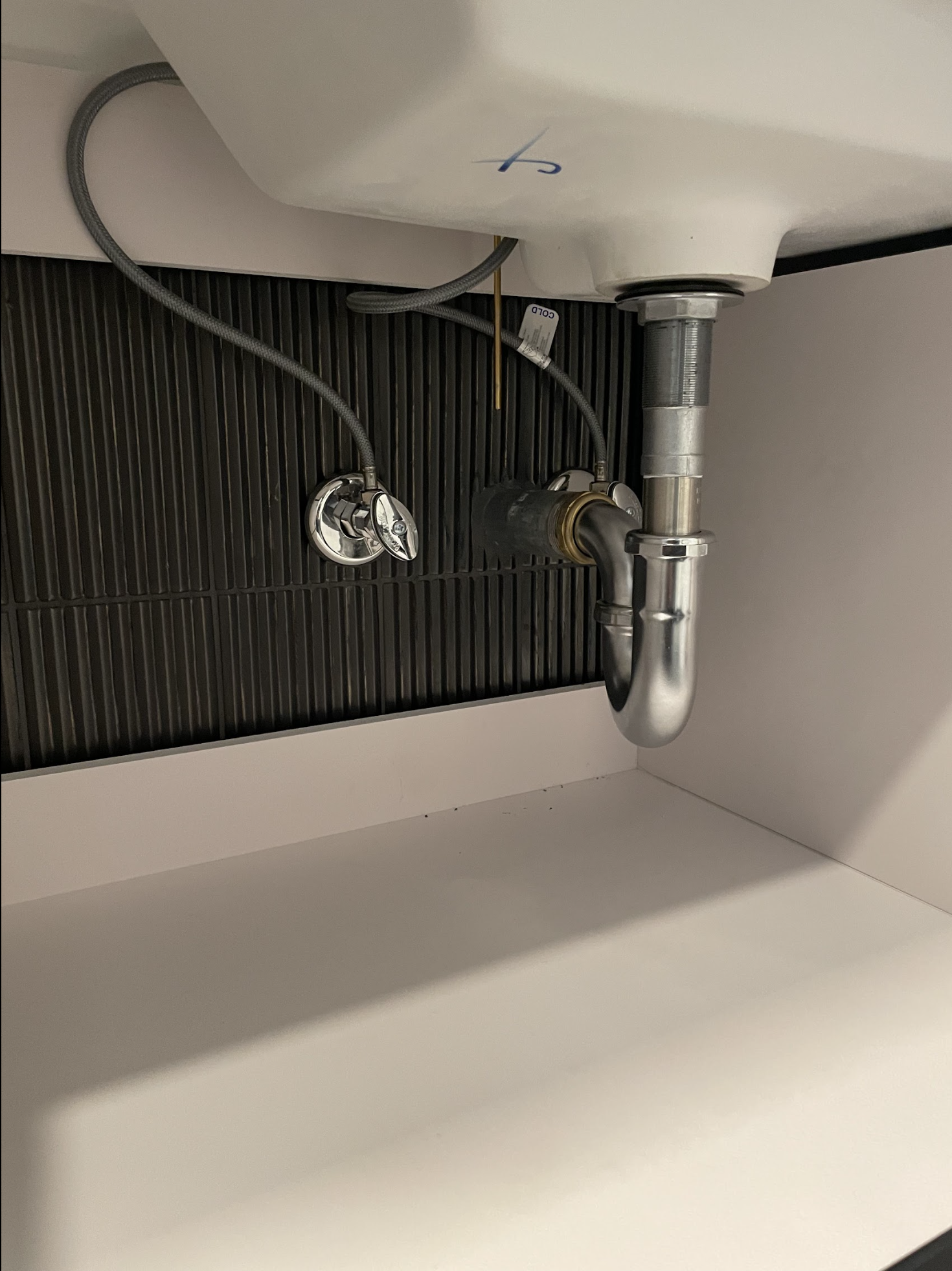 New chrome P-trap and supply lines installed under bathroom vanity in an East Williamsburg loft conversion by We Pipe LLC