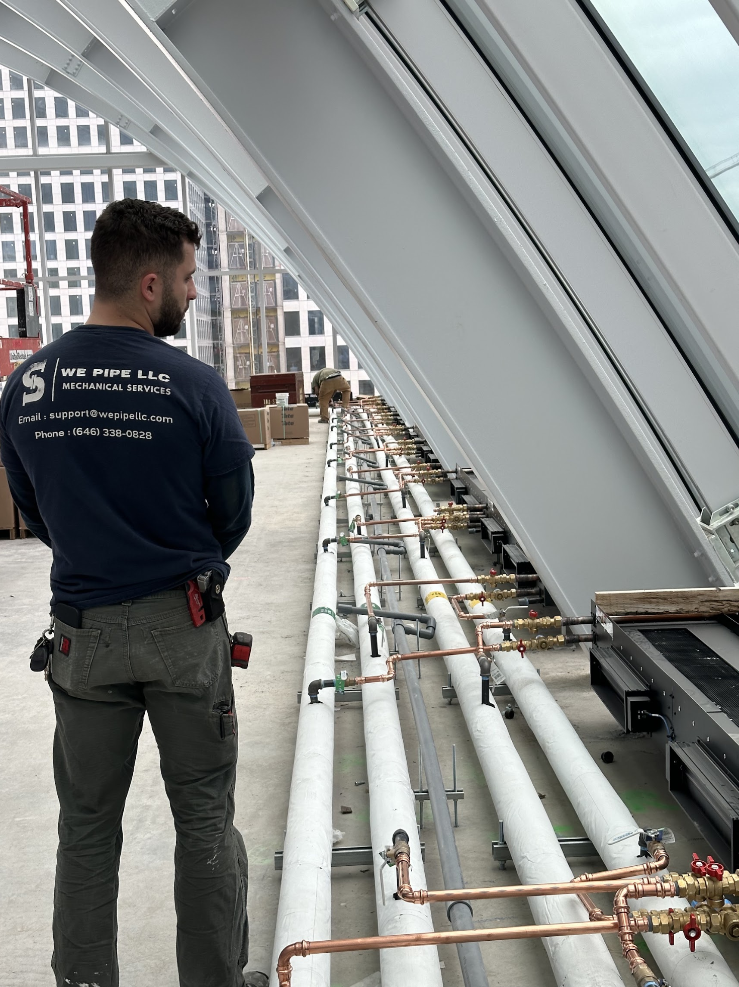 We Pipe LLC technician inspecting copper valve manifolds on a mechanical piping installation in Maspeth, Queens