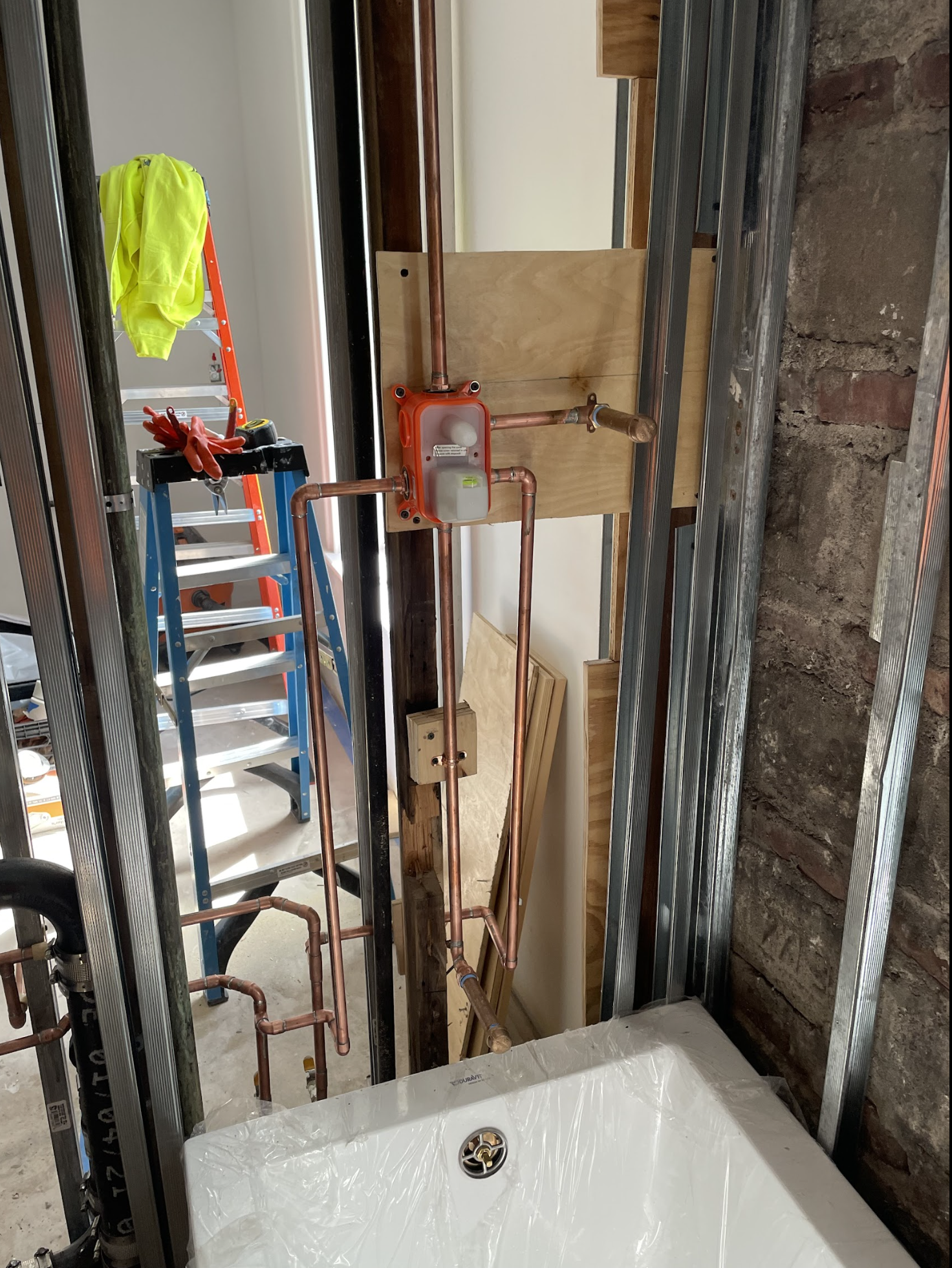 Bathroom rough-in with new toilet set in framed addition in Middle Village Queens, copper supply lines visible in open wall framing