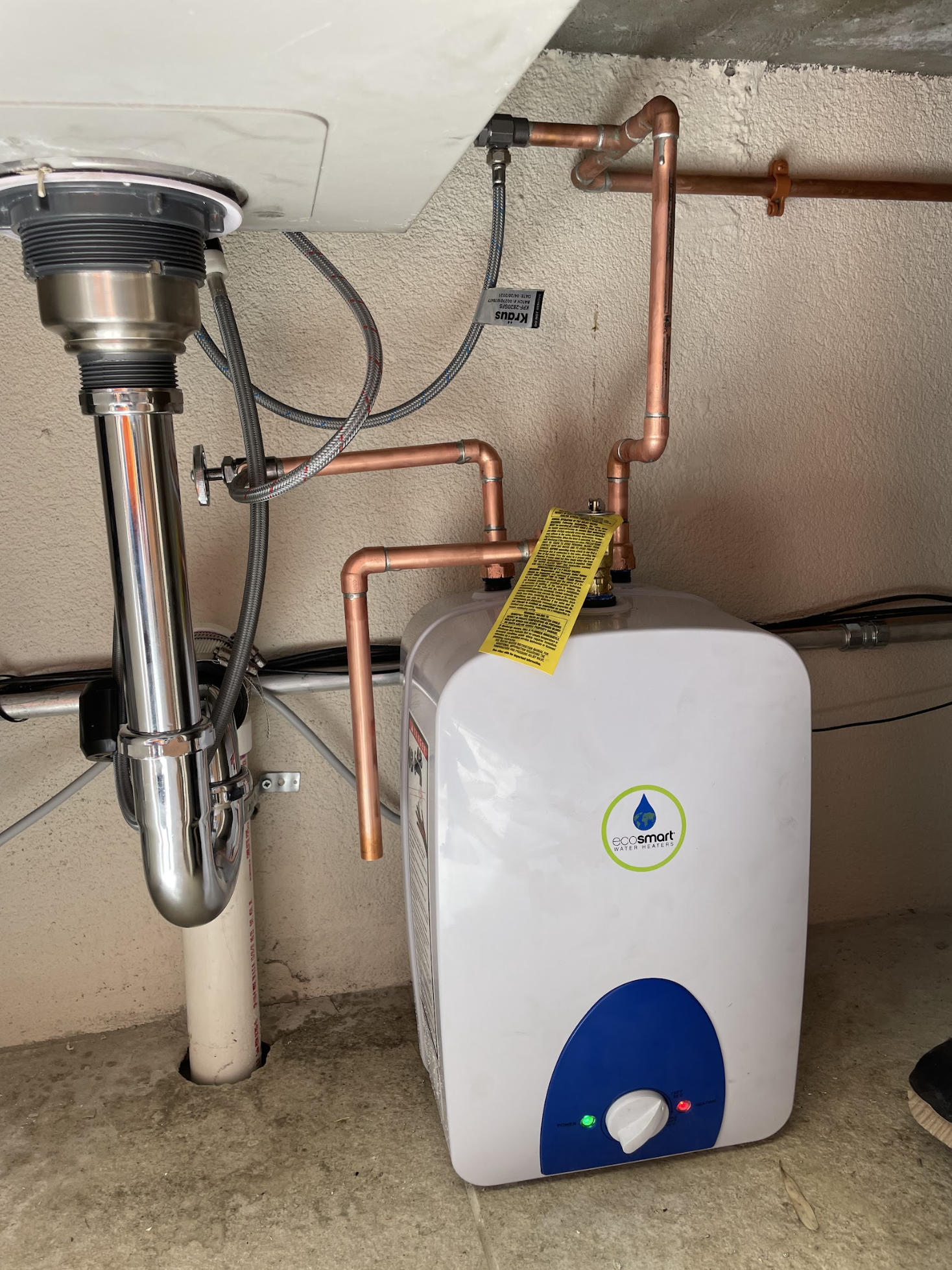 Point-of-use electric water heater installed under bathroom vanity in a Ridgewood three-story row house, copper supply connections by We Pipe LLC