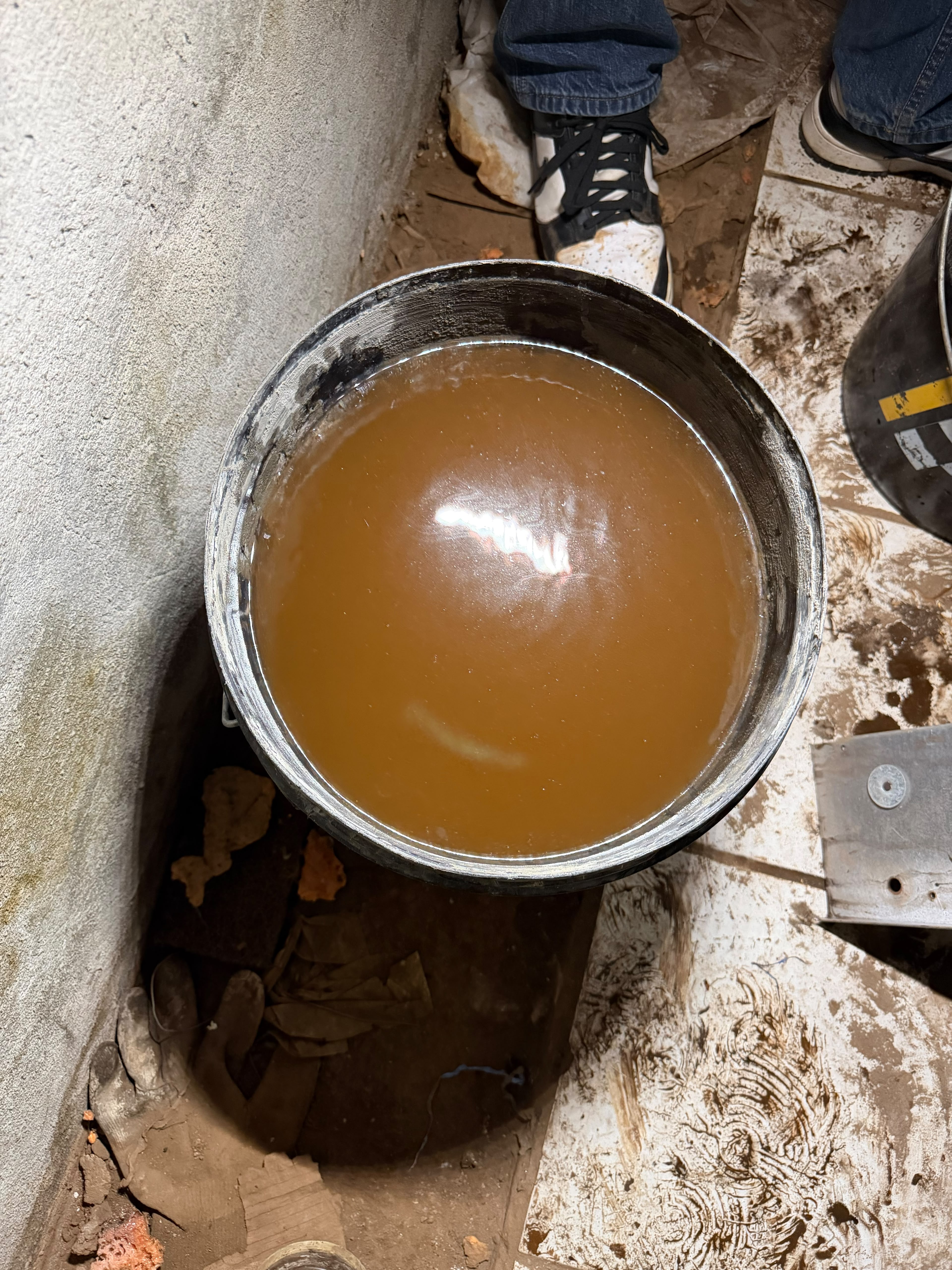 Heavily contaminated boiler water drained during a steam system flush in a Ridgewood pre-war two-family — sediment accumulation that fouled the low water cutoff float