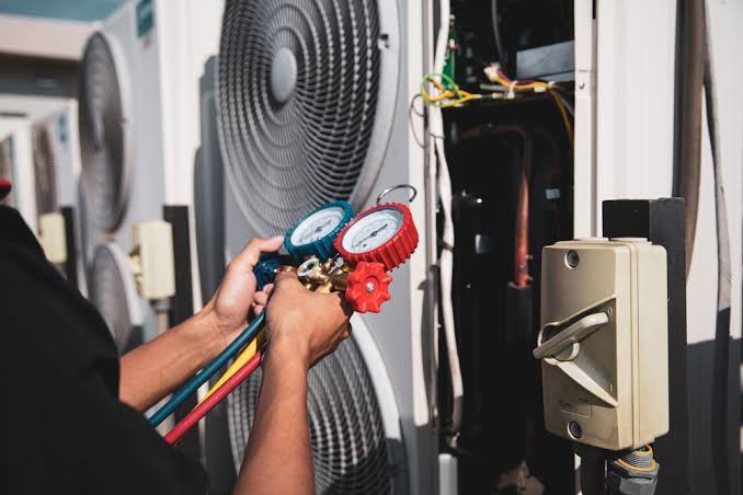 HVAC technician using manifold gauges on commercial air conditioning units, commercial property maintenance in Brooklyn and Queens