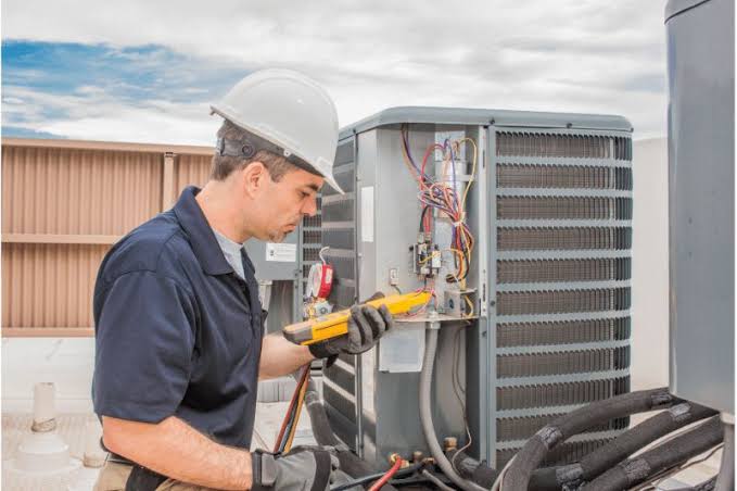 HVAC technician with multimeter diagnosing an outdoor air conditioning unit, HVAC and plumbing diagnostics in Brooklyn and Queens