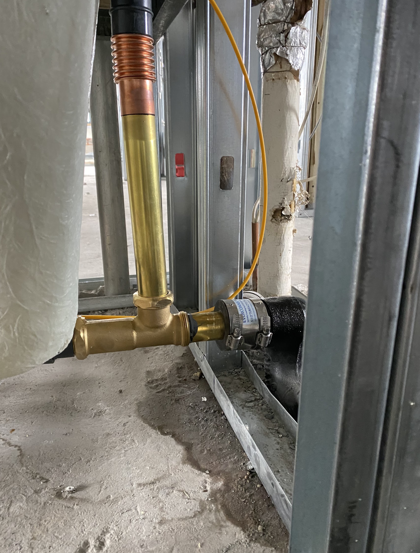 Ceiling-mounted commercial plumbing manifold with multiple ABS branch ports, brass fittings, and copper overhead distribution piping installed in a Williamsburg loft buildout